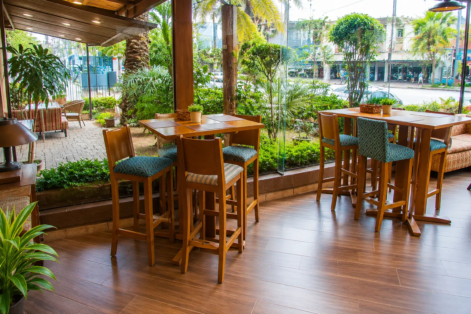 Terraza con jardín y mesas altas de madera